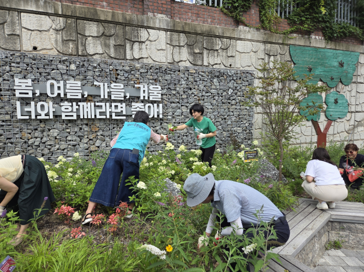 성영신 율천동장과 주민들이 함께 손바닥정원에서 잡초를 뽑는 등 정원을 함께 가꾸고 있다.