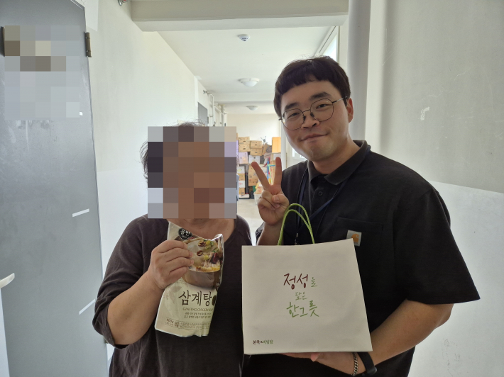 능실종합사회복지관 사회복지사가 지역주민에게 후원물품을 전달하고 있다.