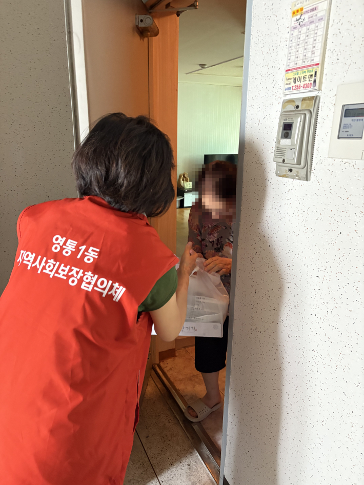 지역사회보장협의체 위원이 독거노인 대상자에게 반찬을 전달하고 있다.