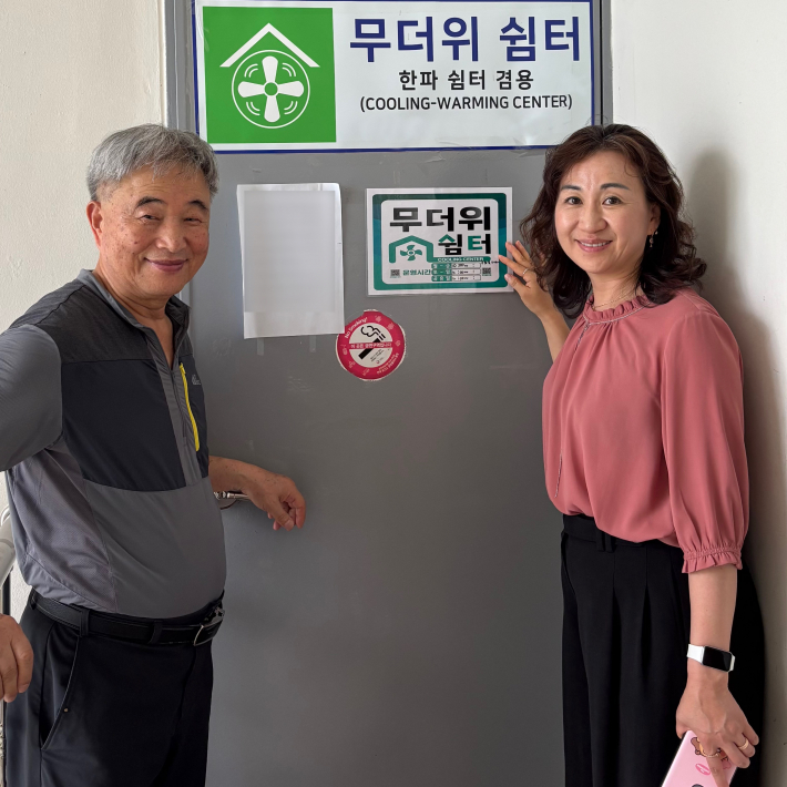 모현희 동장과 한일타운제2경로당 장완수 회장이 무더위쉼터 안내표지를 부착하고 있다.