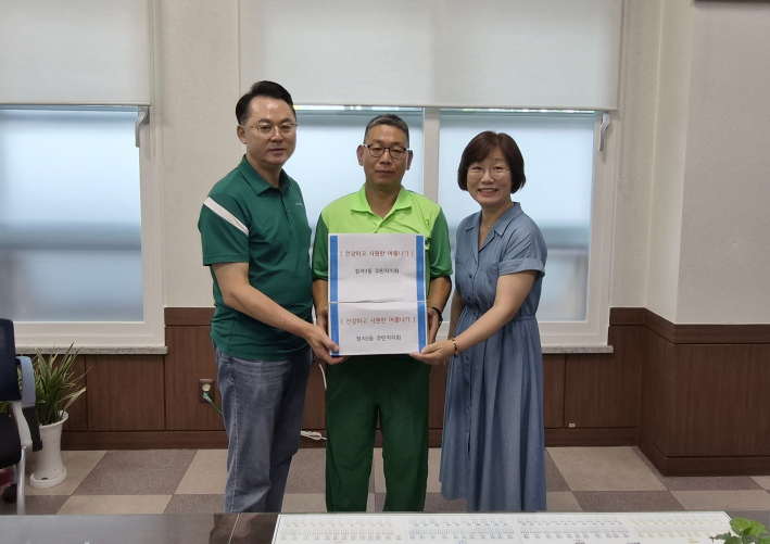 이판수 정자3동 주민자치회장(왼쪽)과 송근숙 정자3동장(오른쪽)이 송기주 환경관리원 반장(가운데)에게 여름맞이 물품을 전달하고 있다.