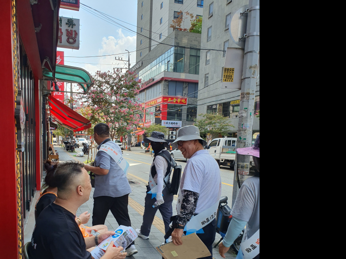외국인 상인들에게 쓰레기 배출방법에 관해 설명하고 있는 모습