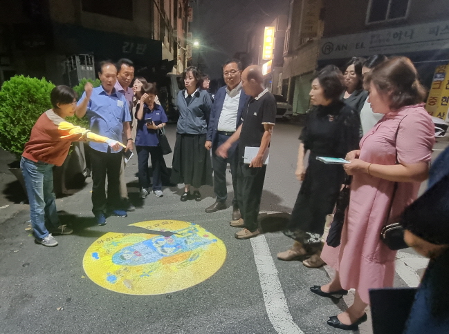 우만1동 주민자치회 관계자와 주민들이 설치된 '토닥토닥 로고젝터'를 함께 바라보고 있다.