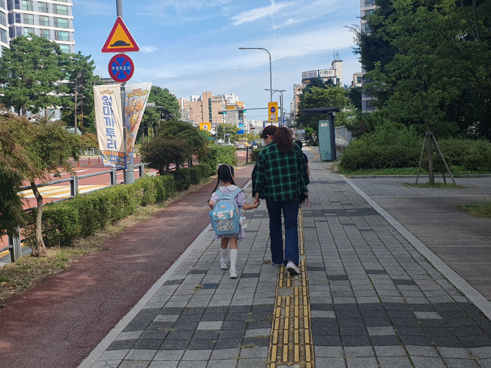 새빛돌보미가 아이의 손을 잡고 학교에서 학원으로 동행돌봄 중이다.