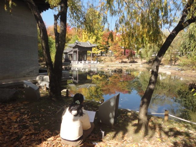 한 관람객이 월방을 병풍처럼 둘러싼 단풍이 연못에 비쳐진 아름다움을 스켓치하고 있다