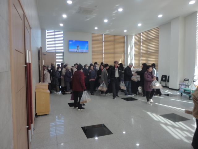 종결 평가회를 마치고 나오는 어르신들에게 복지관에서 준비한 선물을 직원들이 나눠주고있다