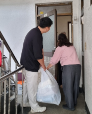 구운동 지역사회보장협의체 위원들이 홀몸 어르신에게 깨끗하게 세탁된 이불을 전달하고 있다