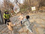 숲 생태해설사와 함께 떨어진 낙엽을 모아 만든 ‘낙엽 풍선’을 하늘로 띄우며 신나게 뛰어노는 아이들의 모습.