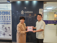 매탄1동 김은정 동장이 송이비인후과의원(원장 송선복)에 '매일1004' 현판을 전달하고 있다