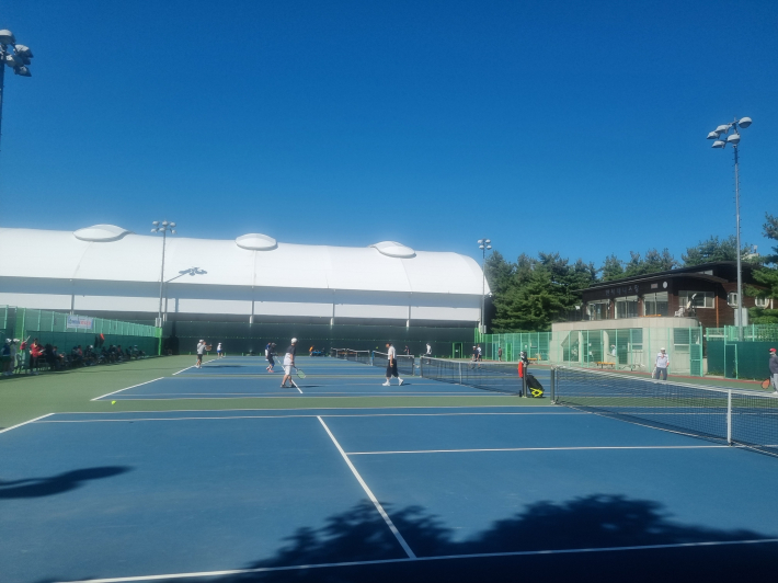 하얀색의 실내 테니스 장과 야외에서의 경기가 대조적이다. 