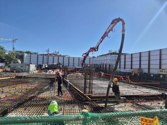 사진) 11일 세류2동 도시재생 어울림센터 지상 1층 복공판 철거 구간에 바닥 슬라브 콘크리트 타설을 하는 모습.    