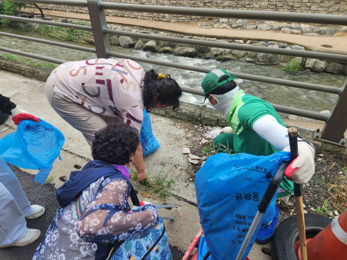 주민과 환경관리원이 함께 수원천 일원을 정비하고 있는 모습