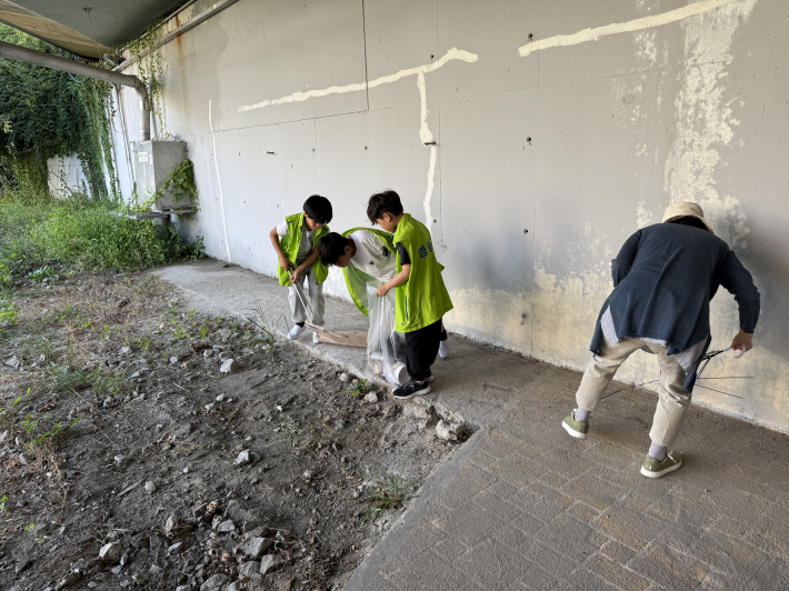아이들과 교사가 원천리천에서 쓰레기를 줍고 있다
