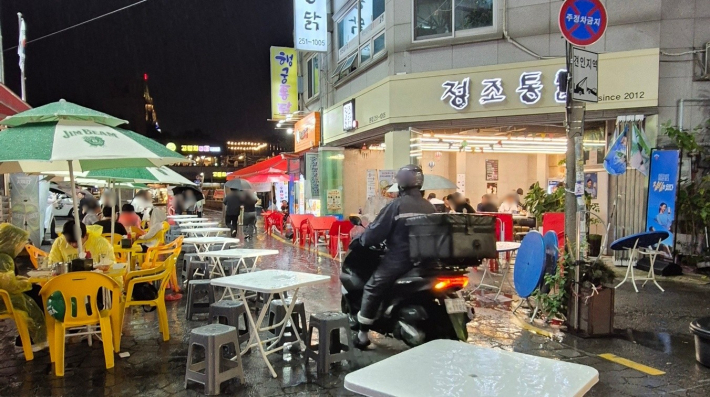 통닭거리에서 버스킹 공연을 즐기며 통닭을 먹는 시민들