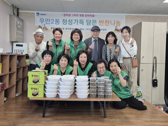 우만2동장과 새마을부녀회원들이 반찬나눔 행사를 기념해 촬영을 하고있다.