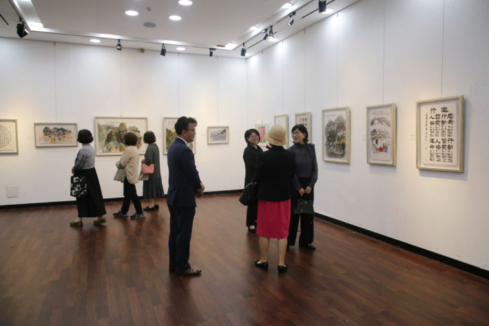 전시장에 전시되어 있는 서예, 그림, 시 작품들을 관람하고 있다.