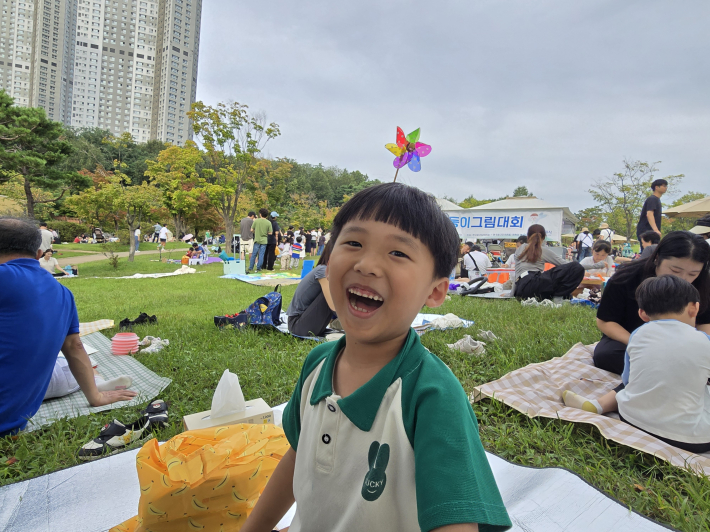 광교호수공원 잔디광장에서 열린 수원둥이 그림대회, 체험부스에서 선물받은 바람개비를 머리에 꽂고 환하게 웃는 어린이
