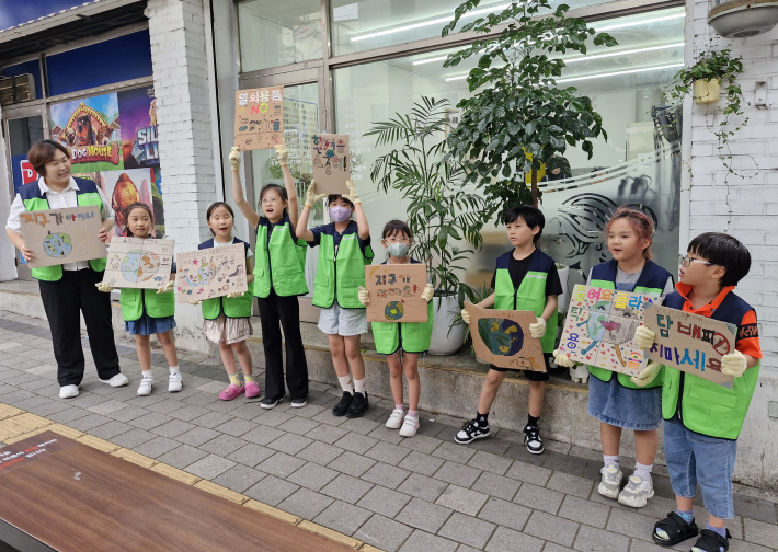 버스정류장 앞에서 시민들에게 환경보호 메세지를 전달하고 있는 아이들 모습