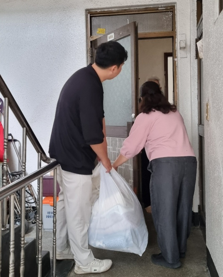 구운동 지역사회보장협의체 위원들이 홀몸 어르신에게 깨끗하게 세탁된 이불을 전달하고 있다