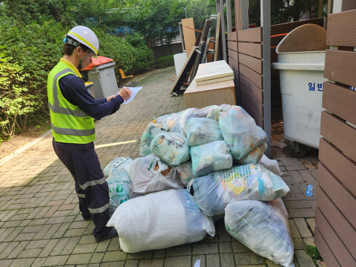 새빛 환경수호자가 한 공동주택단지의 쓰레기 배출량을 현장 점검해 평가표에 적고 있다.