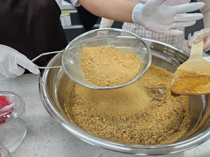 메주가루를 체에받혀 내린다