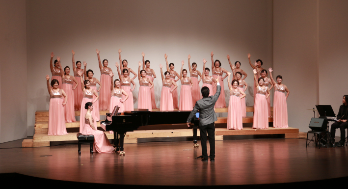 더플러스여성합창단의 연주.  미소 띤 표정과 리드미컬한 손동작이 일품이다.