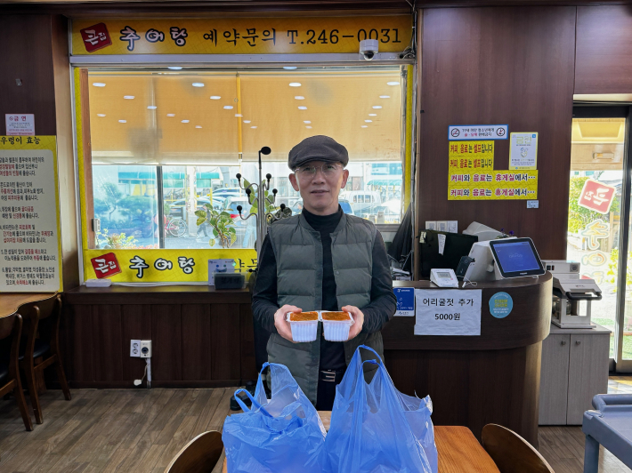 매산동 큰집추어탕에서 추어탕을 전달하며 기념 사진을 찍고 있다.