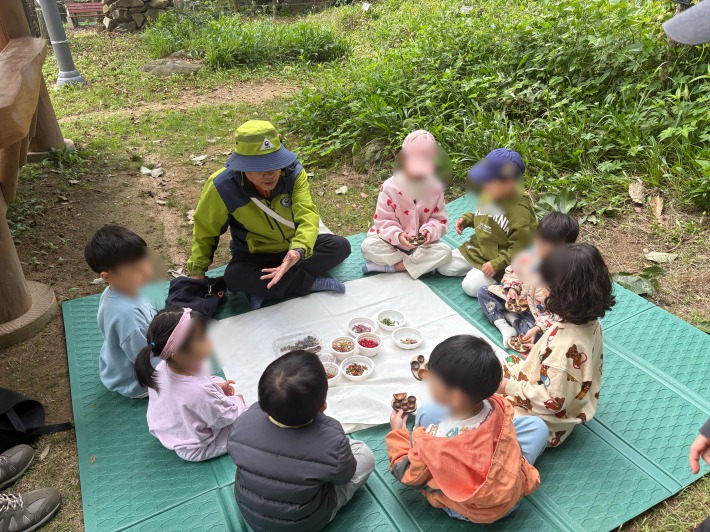 그릇에 열매를 담기 전 숲해설가의 이야기를 듣는 아이들의 모습.