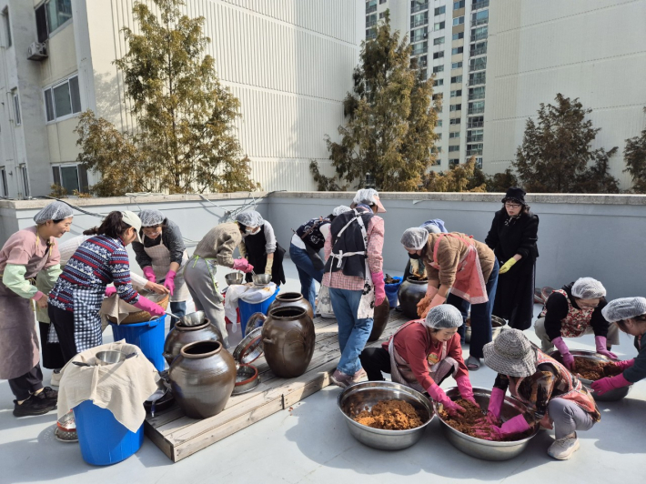 체험 참여자들이 숙성된 된장과 간장을 나누고 있다.