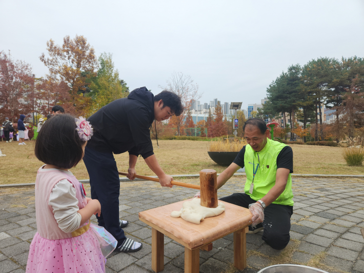차례대로 줄을 지어 떡을 메치는 부모와 아이