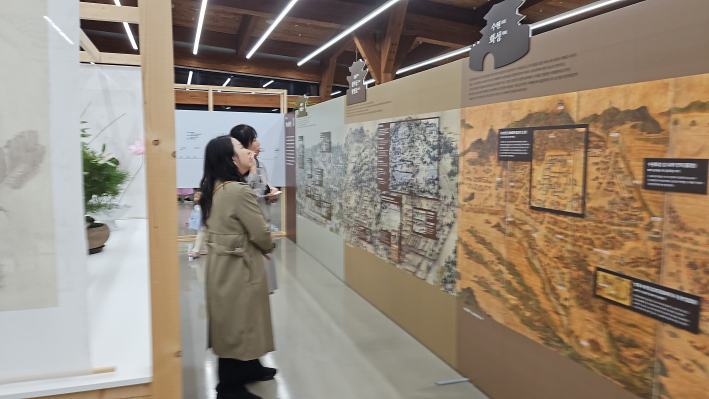 화성행궁의 조경 시설물을 한 눈에 볼 수 있는 화성전도를 보고 있는 관람객