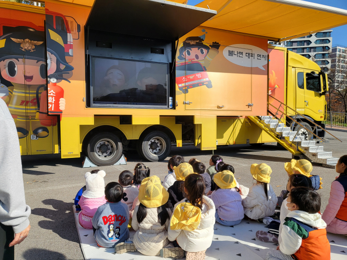 어린이들이 119 이동안전체험차량 앞에서 소방안전 교육 영상을 시청하는 모습.
