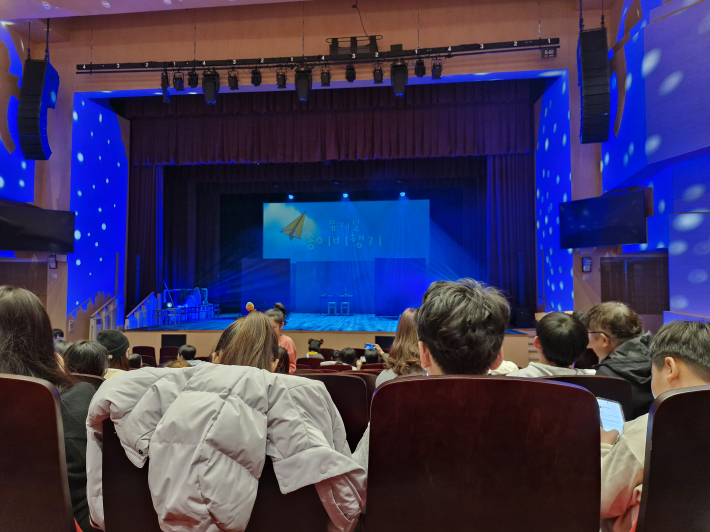 극장 안에서 관객들이 공연 시작을 기다리고 있다.