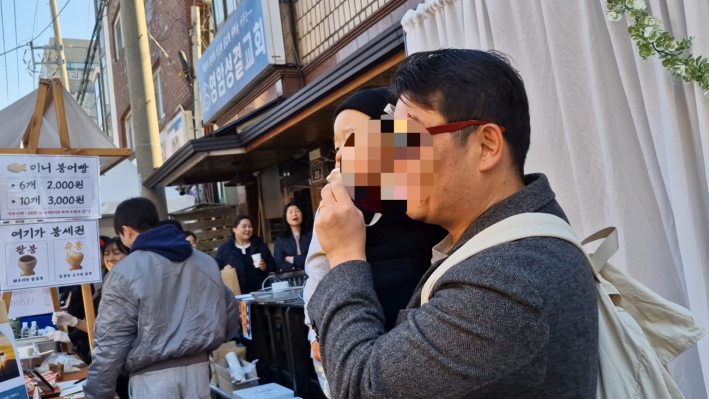 한 아빠가 아이를 안고 웃으면서 인생네컷을 찍고 있다