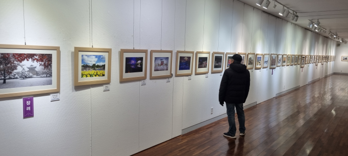 발걸음을 멈추며 사진 작품 감상에 집중하는 관람객