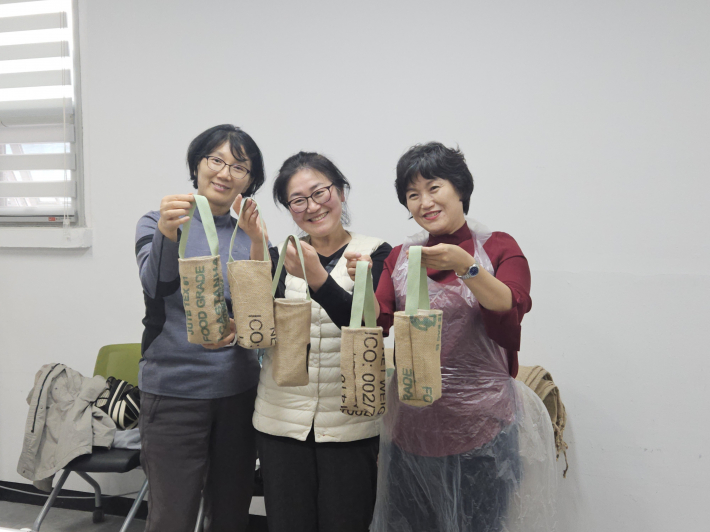 수업에 참가한 봉사자들이 2번째 교육을 받고 완성한 텀블러 가방을 들고 기념 사진을 찍고 있다.