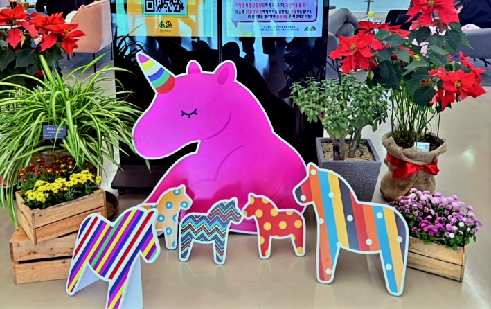 방문자센터 안에서 본 붉은 포인세티아와 그 옆에 놓인 말 모양의 패널 오너먼트