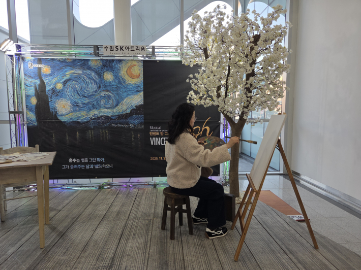 캔버스 앞에 앉아있는 관람객