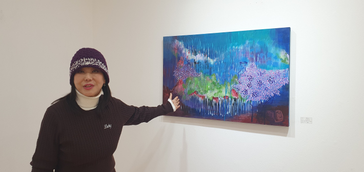 비가 내리는 듯 물감이 흘러내리는 기법을 설명하는 작가의 모습. 멈춰 있는 화폭에 흐르는 시간을 담아내려는 작가의 의도가 엿보인다.