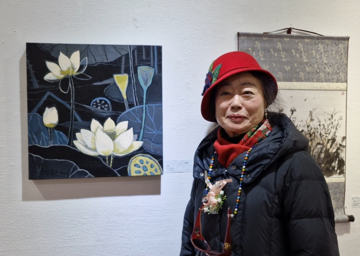신현옥 고문의 '인연' 유화 작품 앞에서 웃고 있다.
