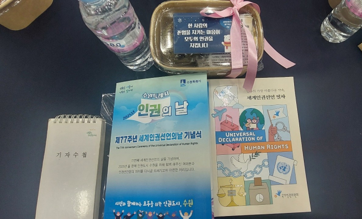 원탁 테이블 11개에 88석에 놓인 기념식 참가자 제공 자료.  맨 우측 책자는  '인류의 가장 아름다운 약속, 세계인권선언 필사' 책자(국가인권위원회 발행)