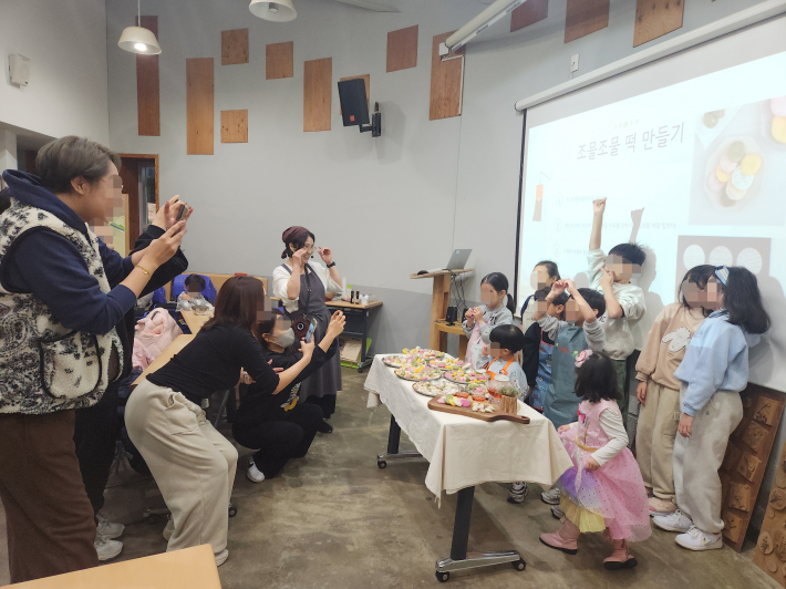 완성된 떡 앞에서 뿌듯한 아이들과 사진을 찍어주는 부모들의 모습