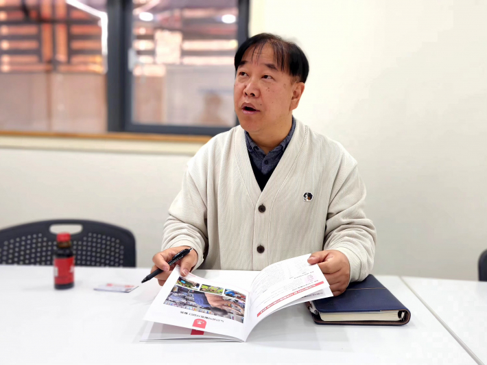 신민우 부장이 노인일자리 및 사회활동지원사업 안내 자료를 설명하며 인터뷰에 응하고 있다. 