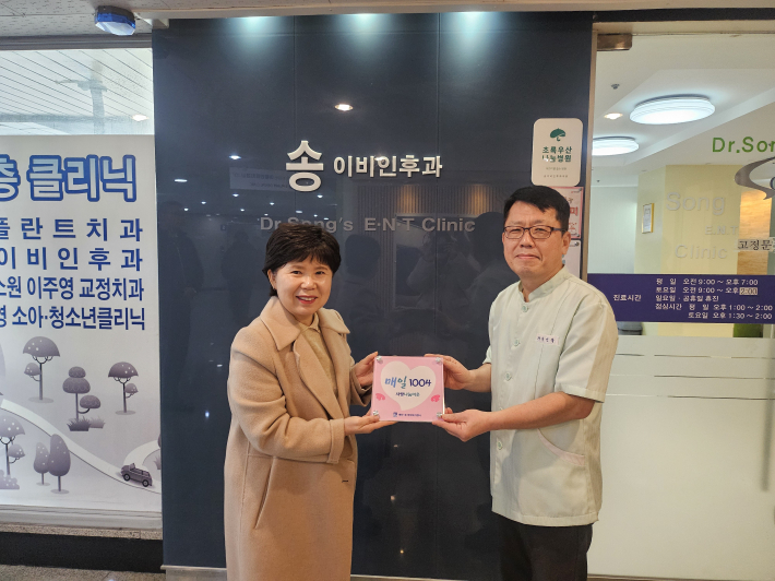 매탄1동 김은정 동장이 송이비인후과의원(원장 송선복)에 '매일1004' 현판을 전달하고 있다