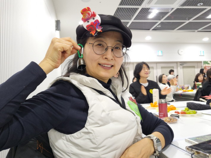 박미선 봉사자가 퀴즈 이벤트에서 받은 마스코트 상품을 들어 보이며 환한 미소를 짓고 있다.