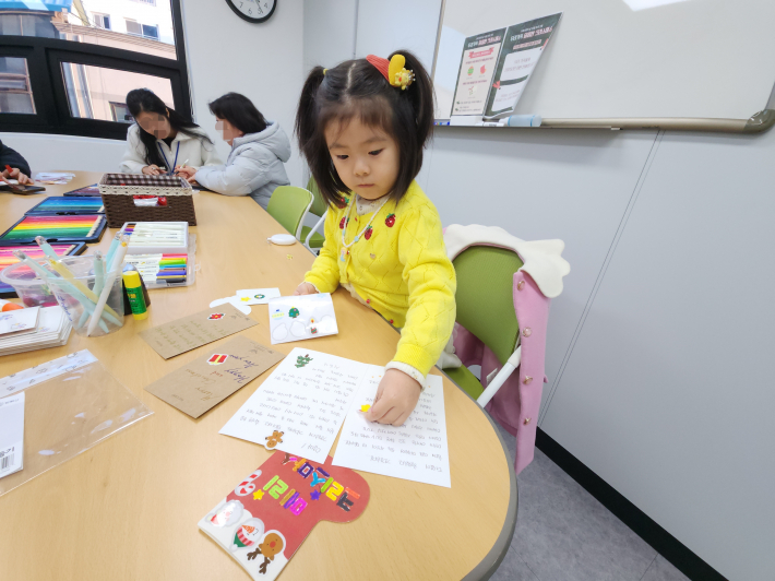 필자 부부가 작성한 크리스마스 카드와 색깔 펜으로 예쁘게 꾸민 양말 카드에 스티커를 붙이는 모습