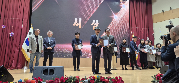 수상자를 축하하고 덕담 나누며 미소를 띠며 기념사진을 남기는 장면