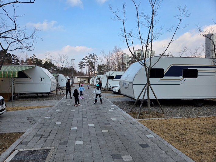캠핑장 내에 인라인, 퀵보드, 자전거를 즐기는 어린이들 모습