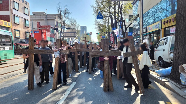 대형 나무 십자가를 짊어지고 행진하는 청년들의 비장하면서도 열정적인 모습이다.