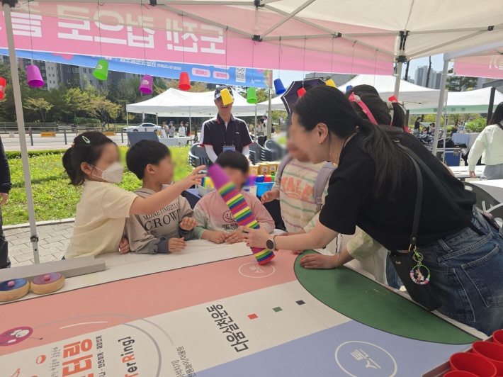 형형색색의 컵을 활용한 체험 부스에서 아이들이 집중하며 활동에 참여하고 있다.